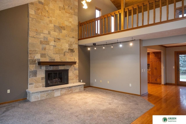 unfurnished living room featuring a stone fireplace, high vaulted ceiling, and wood-type flooring