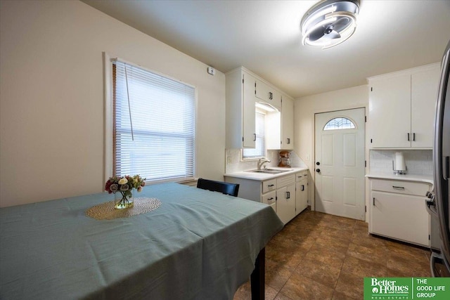 kitchen featuring decorative backsplash, plenty of natural light, white cabinets, and sink