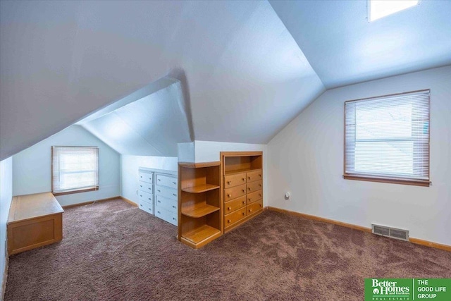 additional living space with dark colored carpet and lofted ceiling