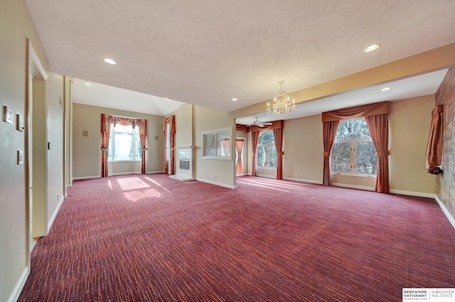 interior space featuring carpet flooring, plenty of natural light, a textured ceiling, and an inviting chandelier