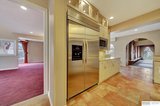 kitchen with light carpet, light brown cabinetry, built in appliances, and plenty of natural light