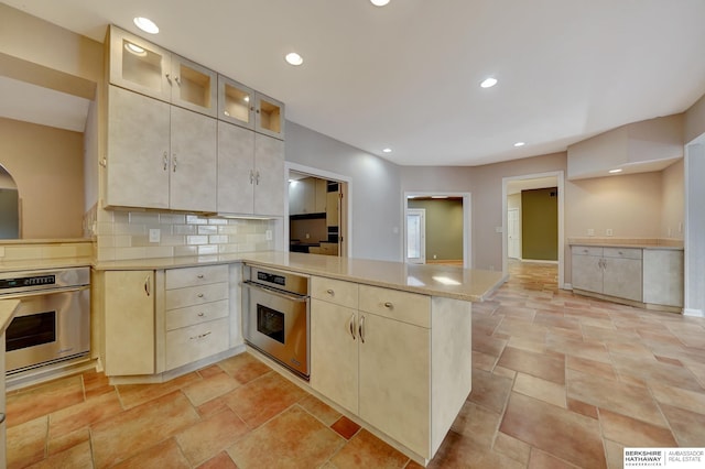 kitchen featuring decorative backsplash, kitchen peninsula, and oven