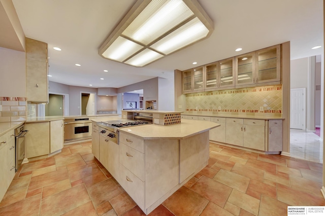 kitchen with decorative backsplash, a center island, kitchen peninsula, and appliances with stainless steel finishes