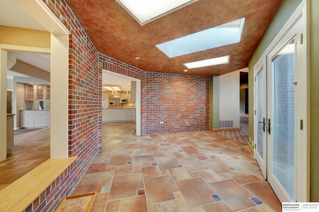 hall featuring a skylight and brick wall