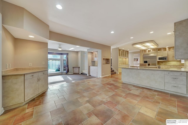 kitchen featuring built in appliances, ceiling fan, and tasteful backsplash