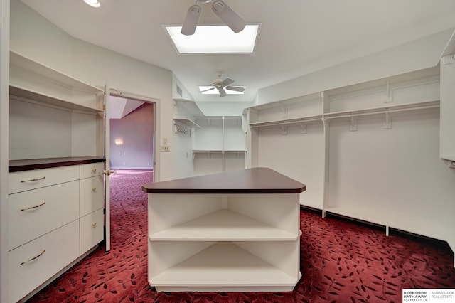 spacious closet with dark colored carpet and ceiling fan