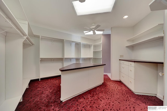 spacious closet with ceiling fan and dark carpet