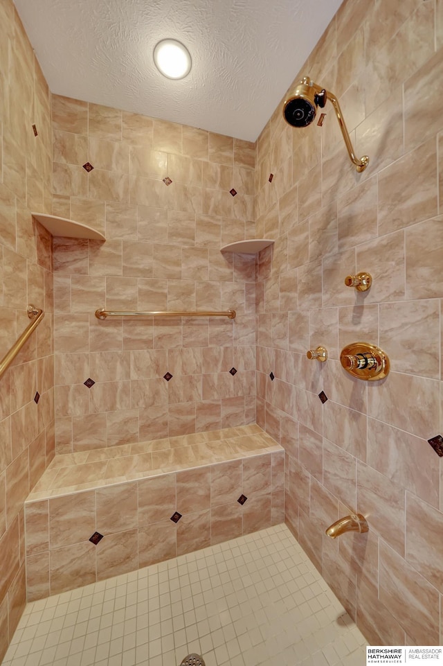 bathroom with a textured ceiling and tiled shower