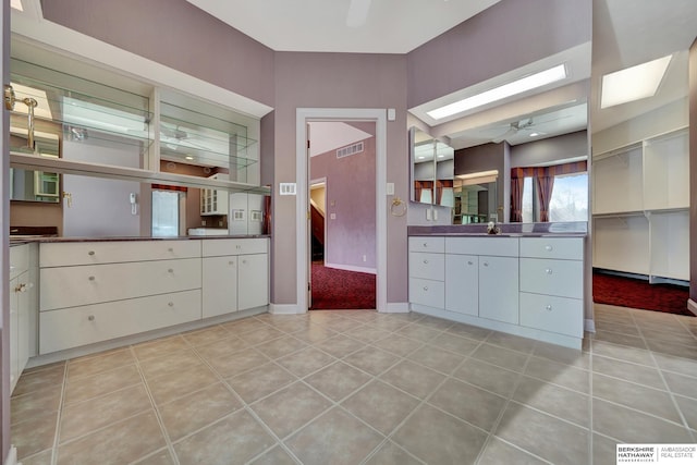 bathroom featuring tile patterned flooring, vanity, a skylight, and ceiling fan