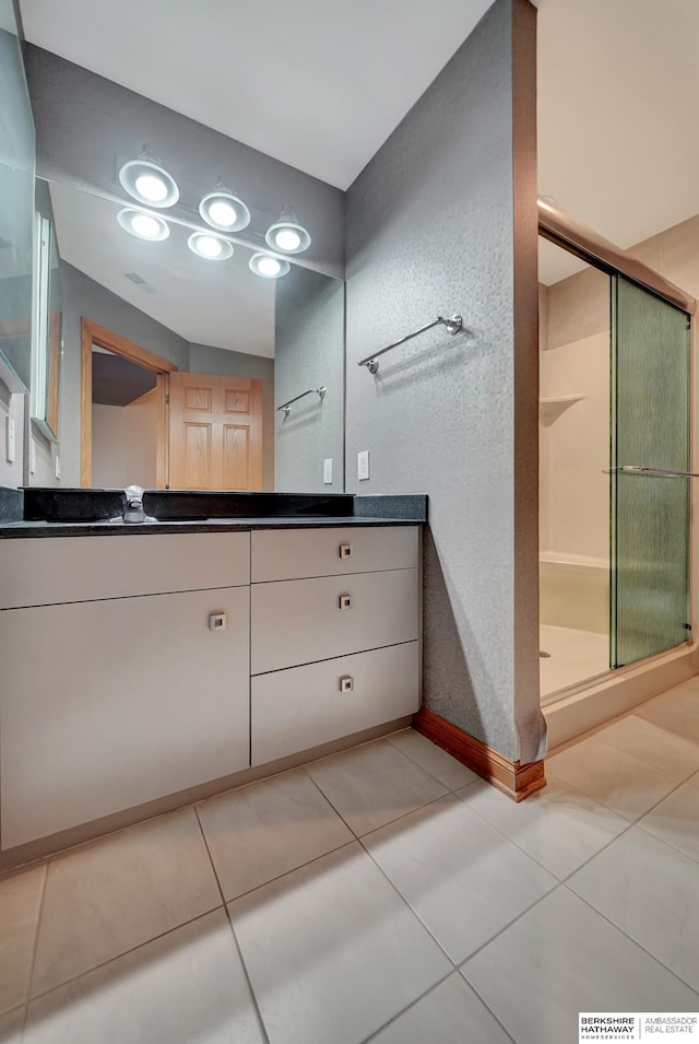 bathroom featuring tile patterned flooring, vanity, and walk in shower