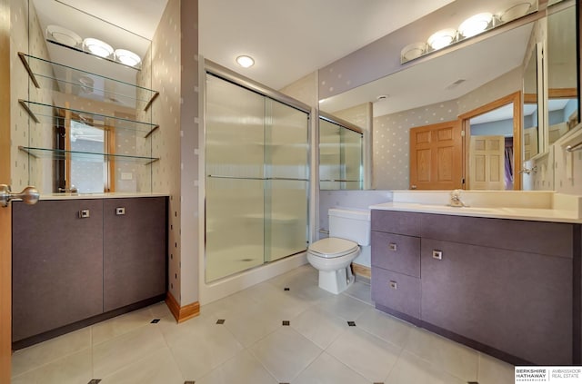 bathroom with tile patterned floors, vanity, toilet, and walk in shower