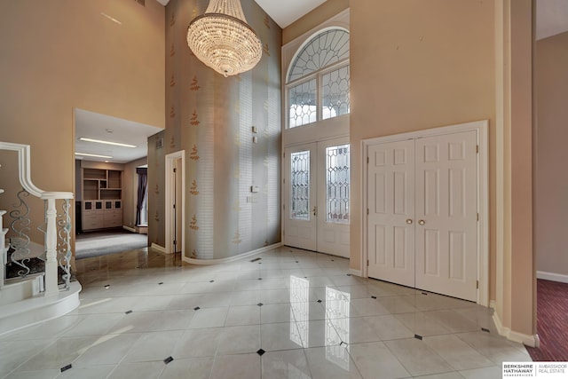 foyer with a towering ceiling, an inviting chandelier, and light tile patterned flooring