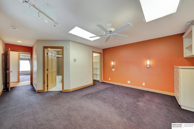 carpeted spare room featuring a skylight and ceiling fan