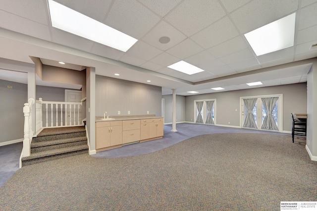 basement featuring carpet floors, a drop ceiling, and sink