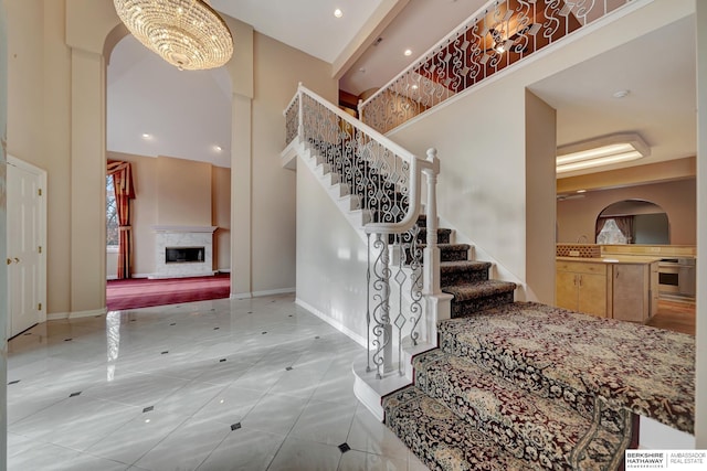 entryway with a high end fireplace, a high ceiling, and an inviting chandelier