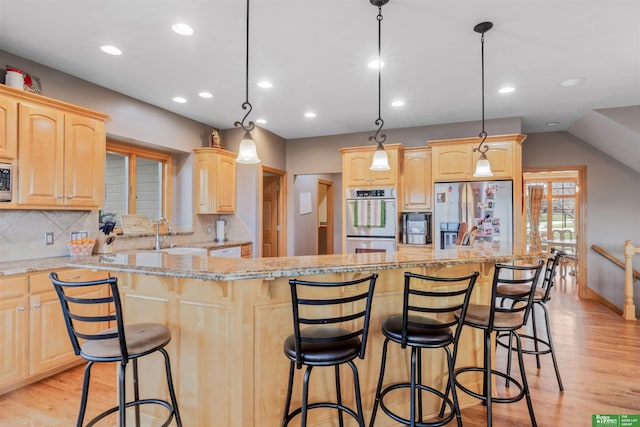 kitchen featuring pendant lighting, light brown cabinets, light hardwood / wood-style floors, and stainless steel appliances