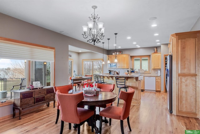 dining area with light hardwood / wood-style flooring, a wealth of natural light, and an inviting chandelier