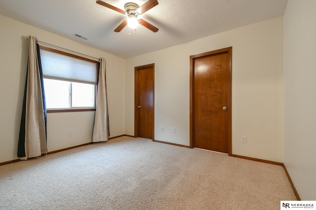 unfurnished bedroom with ceiling fan, light colored carpet, and a textured ceiling