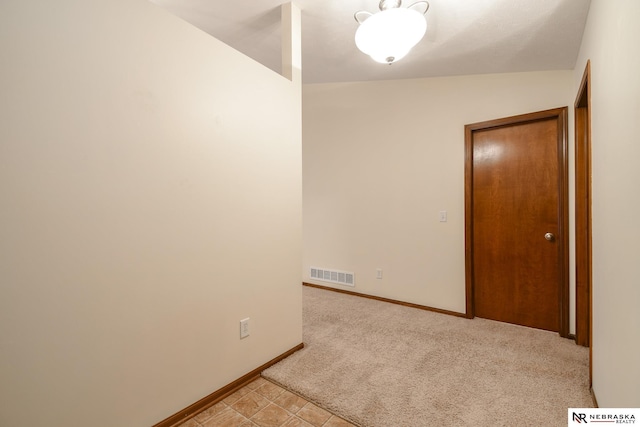 unfurnished room with light colored carpet and vaulted ceiling