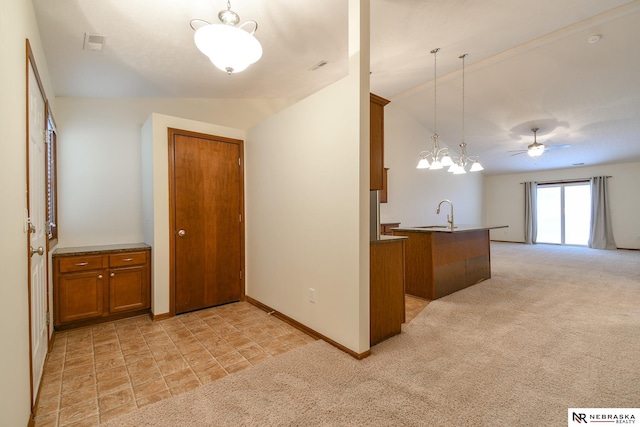 kitchen with pendant lighting, ceiling fan with notable chandelier, light carpet, and vaulted ceiling