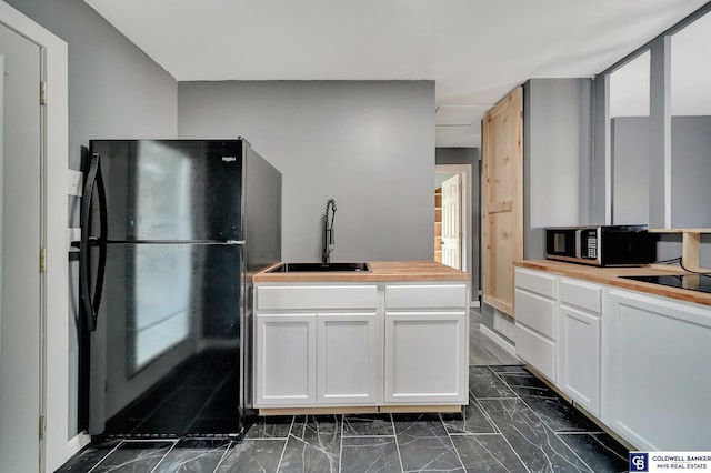 kitchen with white cabinetry, sink, and black appliances