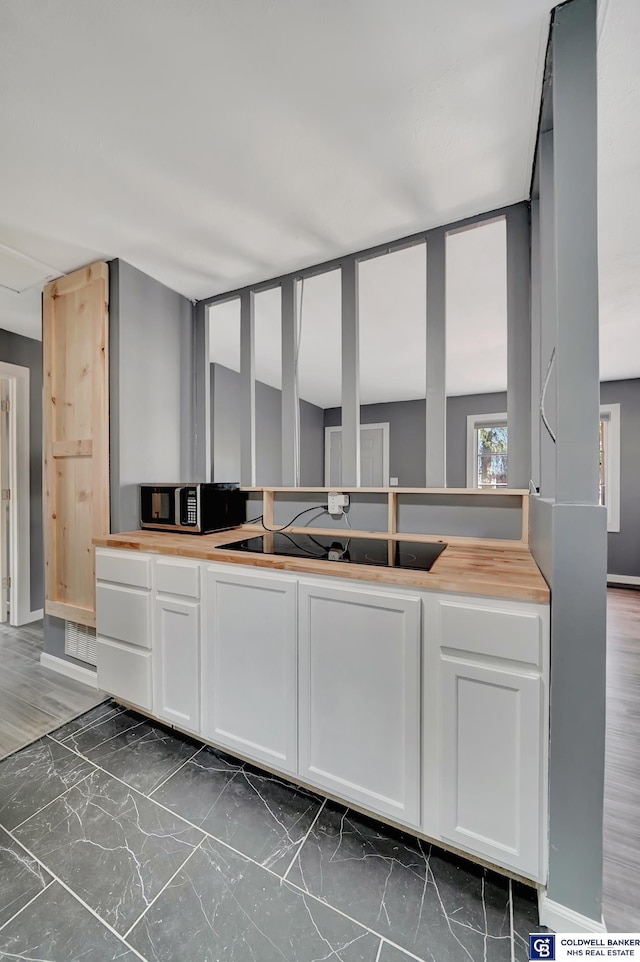 kitchen featuring butcher block counters, white cabinetry, and dark hardwood / wood-style floors