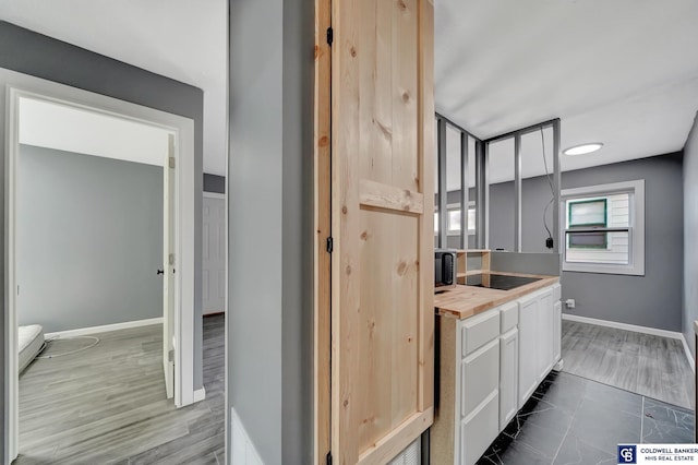 kitchen with white cabinets, wood counters, dark hardwood / wood-style flooring, and black electric cooktop