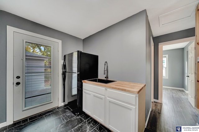 kitchen featuring wooden counters, white cabinets, black refrigerator, sink, and dark hardwood / wood-style floors