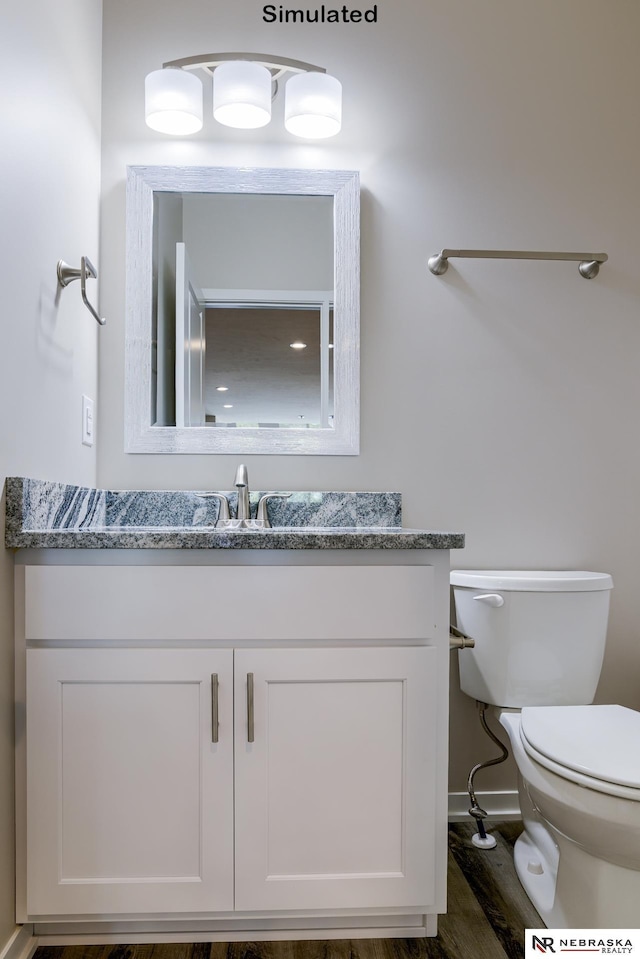 bathroom with wood-type flooring, vanity, and toilet