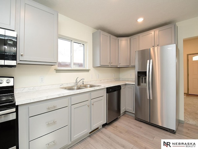 kitchen with gray cabinets, sink, stainless steel appliances, and light wood-type flooring