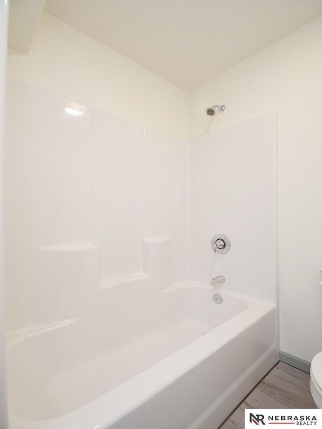 bathroom featuring hardwood / wood-style floors, tub / shower combination, and toilet