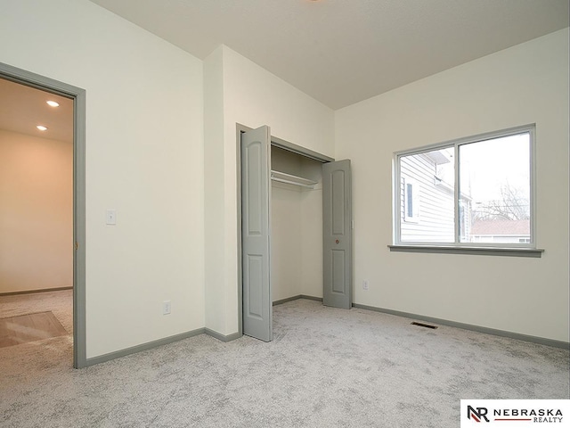 unfurnished bedroom with light colored carpet and a closet