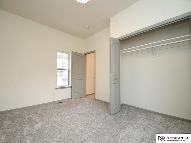 unfurnished bedroom with a closet and light colored carpet