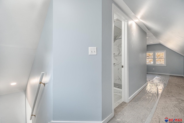 hallway with carpet floors and vaulted ceiling