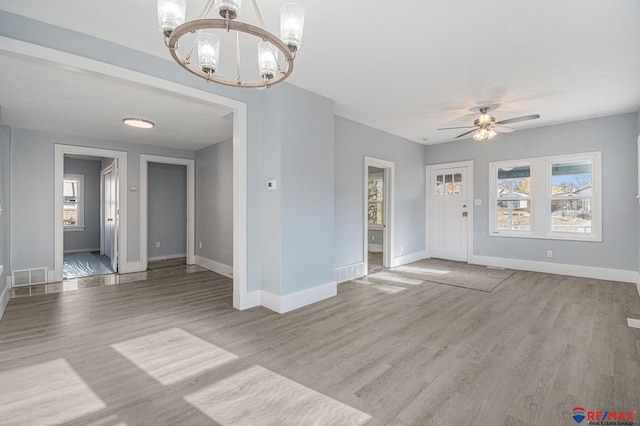 empty room with ceiling fan with notable chandelier and light hardwood / wood-style floors