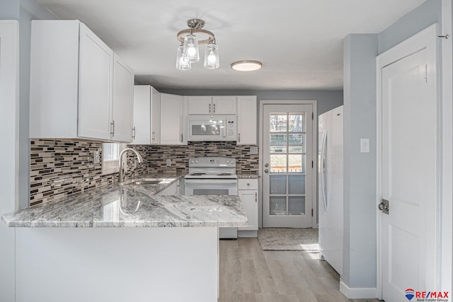 kitchen with kitchen peninsula, white cabinetry, sink, and white appliances