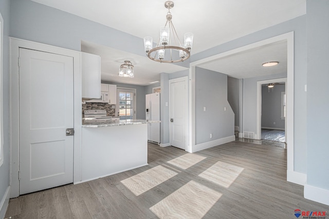 kitchen featuring decorative backsplash, light wood-type flooring, white appliances, a notable chandelier, and white cabinets