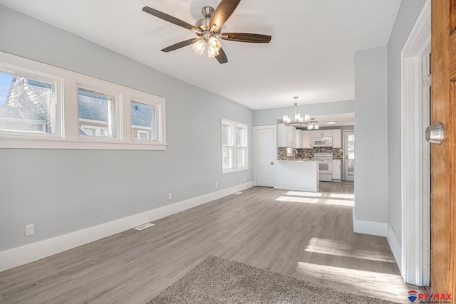 unfurnished living room with light hardwood / wood-style flooring and ceiling fan with notable chandelier