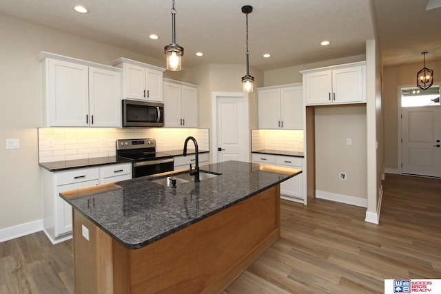 kitchen featuring stainless steel appliances, white cabinetry, and dark stone counters