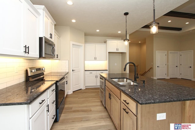 kitchen with stainless steel appliances, sink, pendant lighting, a center island with sink, and white cabinetry