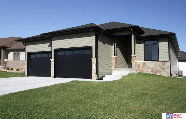 prairie-style home with a front yard, a garage, and cooling unit