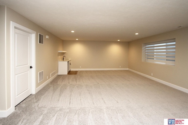 basement featuring sink and light colored carpet