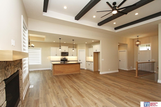 kitchen with white cabinetry, a healthy amount of sunlight, an island with sink, light hardwood / wood-style floors, and appliances with stainless steel finishes