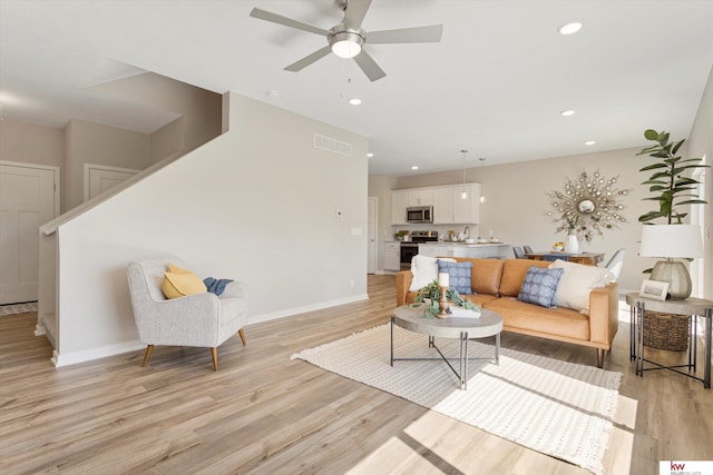 living room with light hardwood / wood-style flooring and ceiling fan