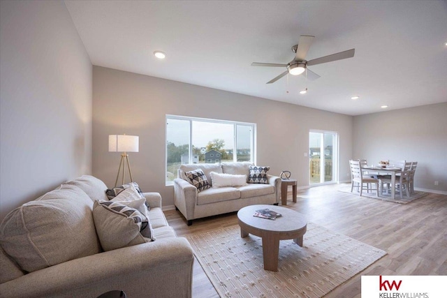 living room with light hardwood / wood-style flooring and ceiling fan