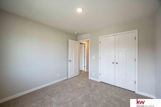 unfurnished bedroom with light carpet and a closet