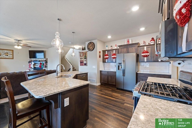 kitchen with sink, tasteful backsplash, an island with sink, pendant lighting, and appliances with stainless steel finishes