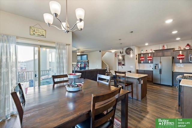 dining space with ceiling fan with notable chandelier and dark hardwood / wood-style flooring