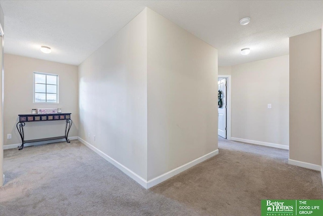 hallway featuring light colored carpet and a textured ceiling