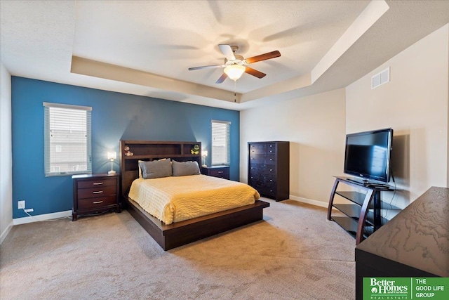 carpeted bedroom with a tray ceiling, ceiling fan, and a textured ceiling